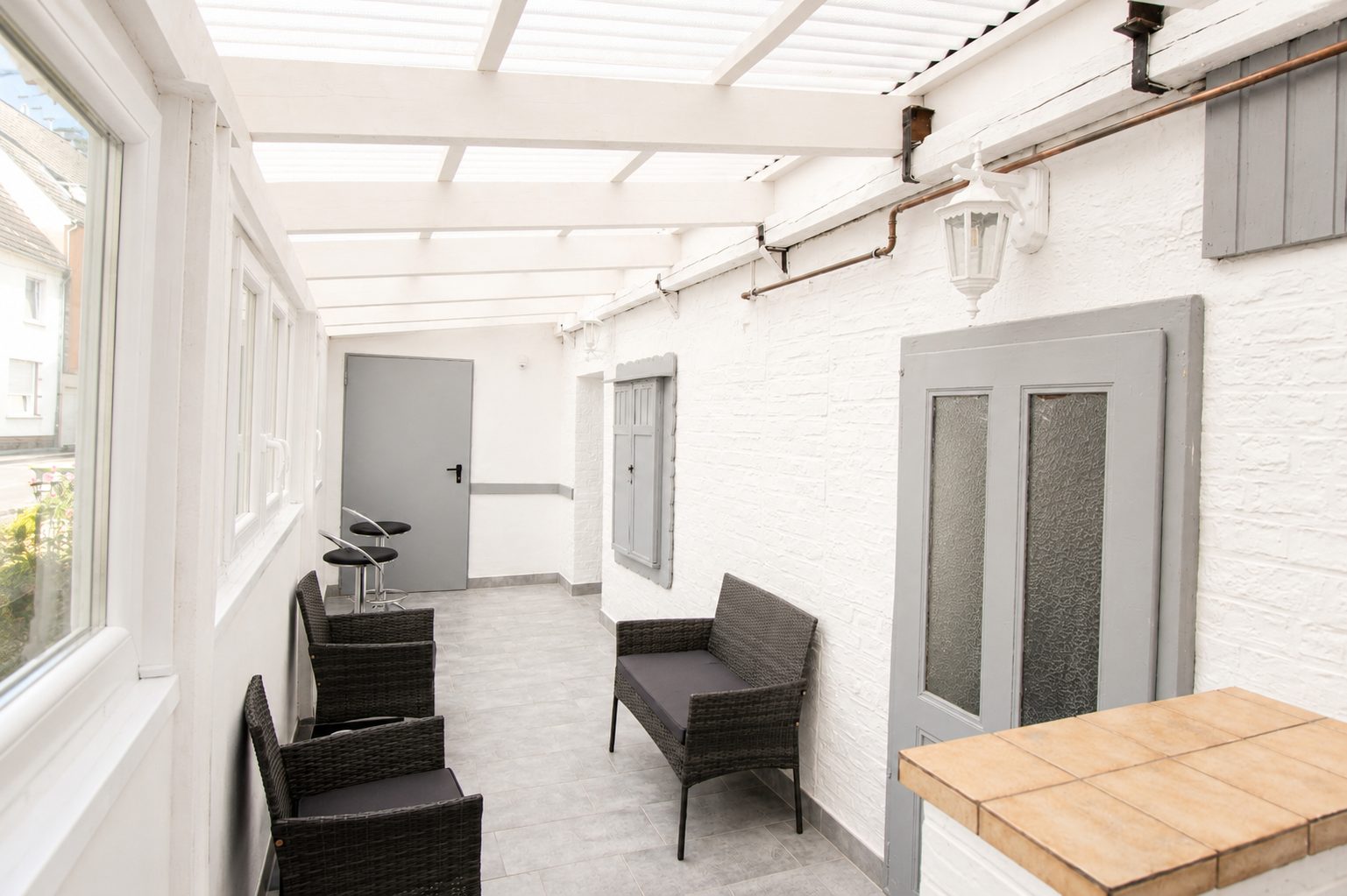Überdachte Terrasse mit Sitzgruppe und Barhockern