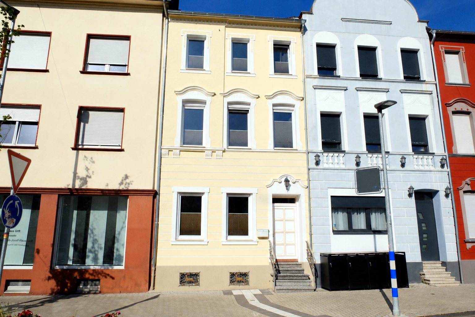 Außenansicht der Unterkunft: gelbe Fassadenfront einer Stadtvilla mit weißen Fensterfaschen und Eingangstreppe